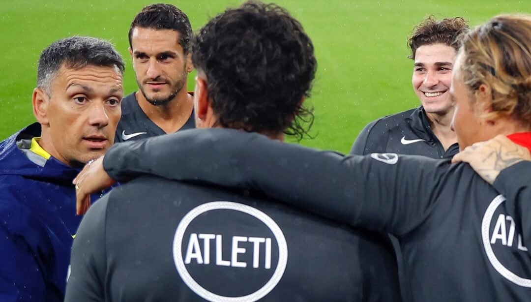 Jugadores del Atlético de Madrid conversan junto al cuerpo técnico durante un entrenamiento previo de la Champions League 2025-26. / Vía: @atleticodemadrid
