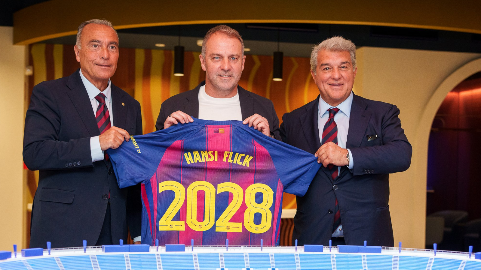 Yuste, Flick y Laporta en el acto de renovación del técnico alemán. Vía: X/@FCBarcelona